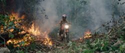 An invader rides his motorcycle through the rainforest fire blaze. (Credit: Alex Pritz/Amazon Land Documentary)